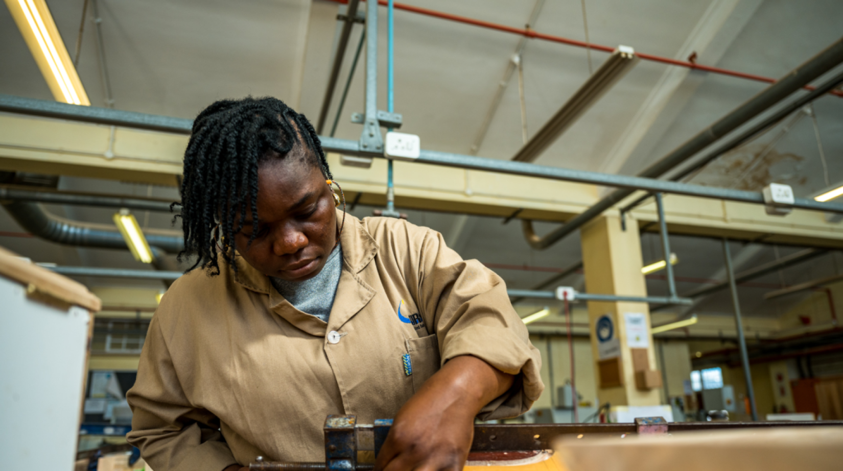 Imagen joven mujer con overoles beige trabaja en un taller de carpintería Pie de foto: El proyecto "Youth Rising", respaldado por la ONU en Liberia, está ayudando a impulsar el empleo juvenil y el emprendimiento como impulsores a largo plazo del desarrollo sostenible. 