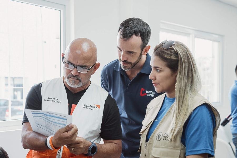 Tres participantes ven un formulario que un participante sostiene en sus brazos, conversan sobre el ejercicio